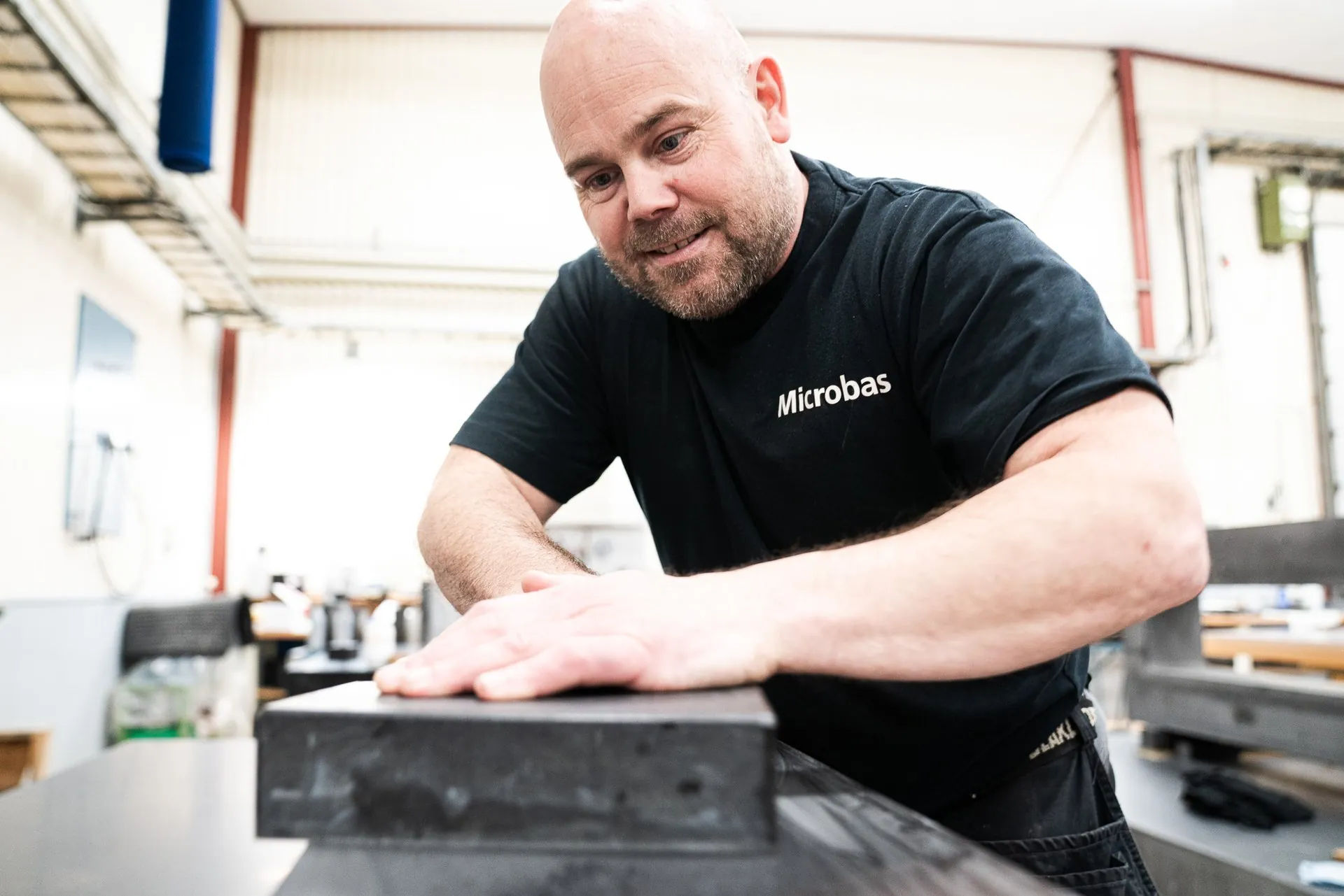 Employee with his hand on a diabase part on a workbench in the workshop