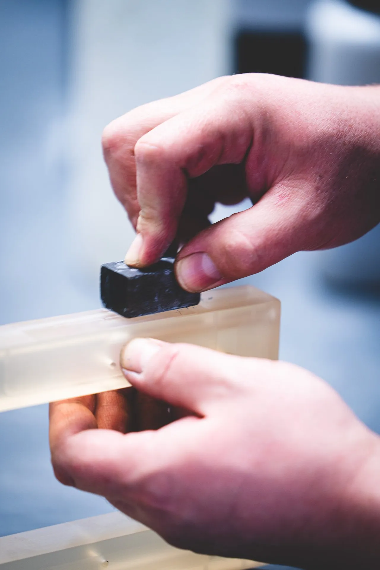 Hands working the edge of a glass-ceramic part with a small grinding stone