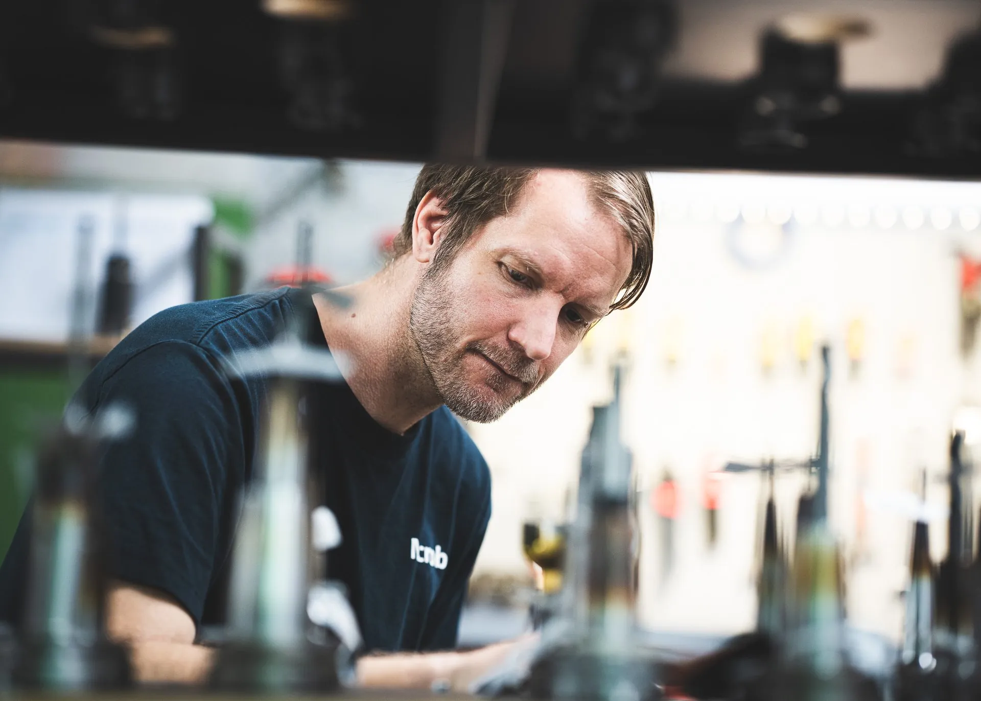 Focused employee at the workbench, framed by machine parts in the foreground