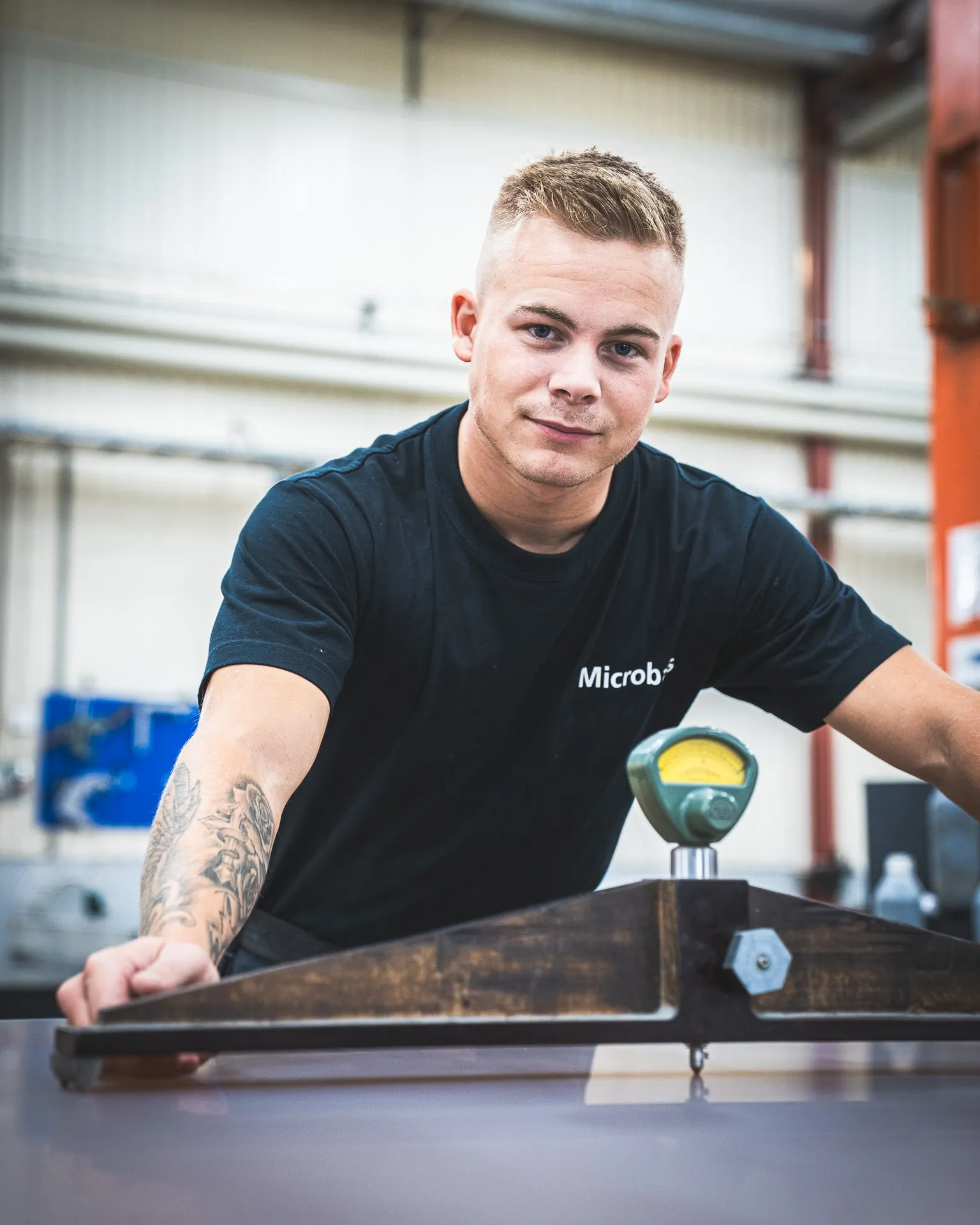 Portrait of a young employee at a measuring bridge with a dial gauge on a large flat surface