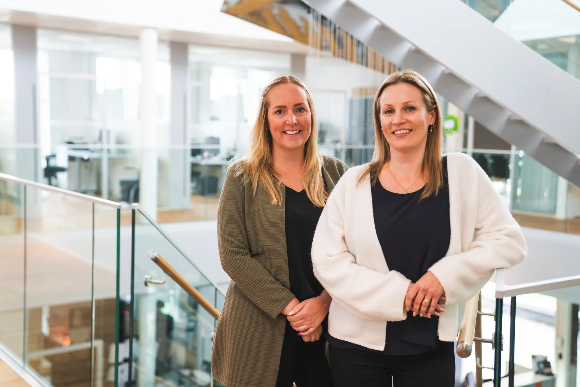 Two Staffanstorps Centrum employees by the glass railing in the open stairwell at Kometen