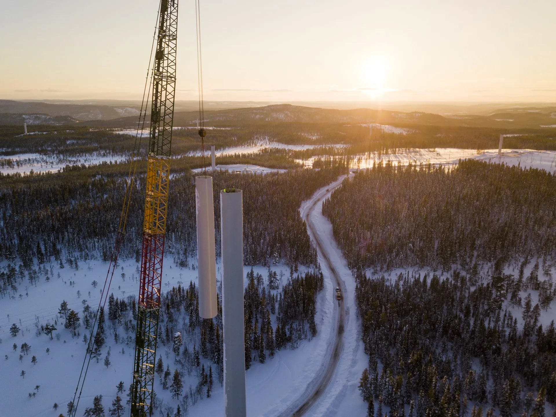Lyftkran reser tornsektion i soluppgång under montage