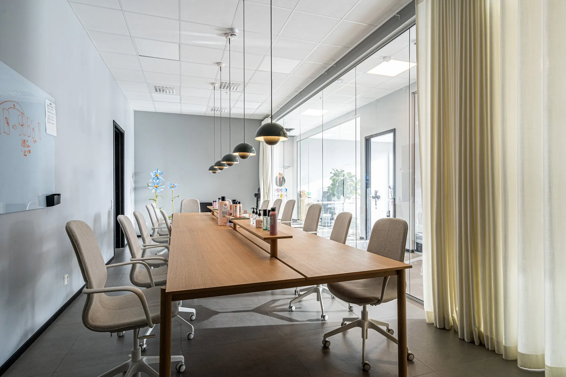 Ljust mötesrum med långbord, designlampor och glasvägg i logistikbyggnadens kontorsdel