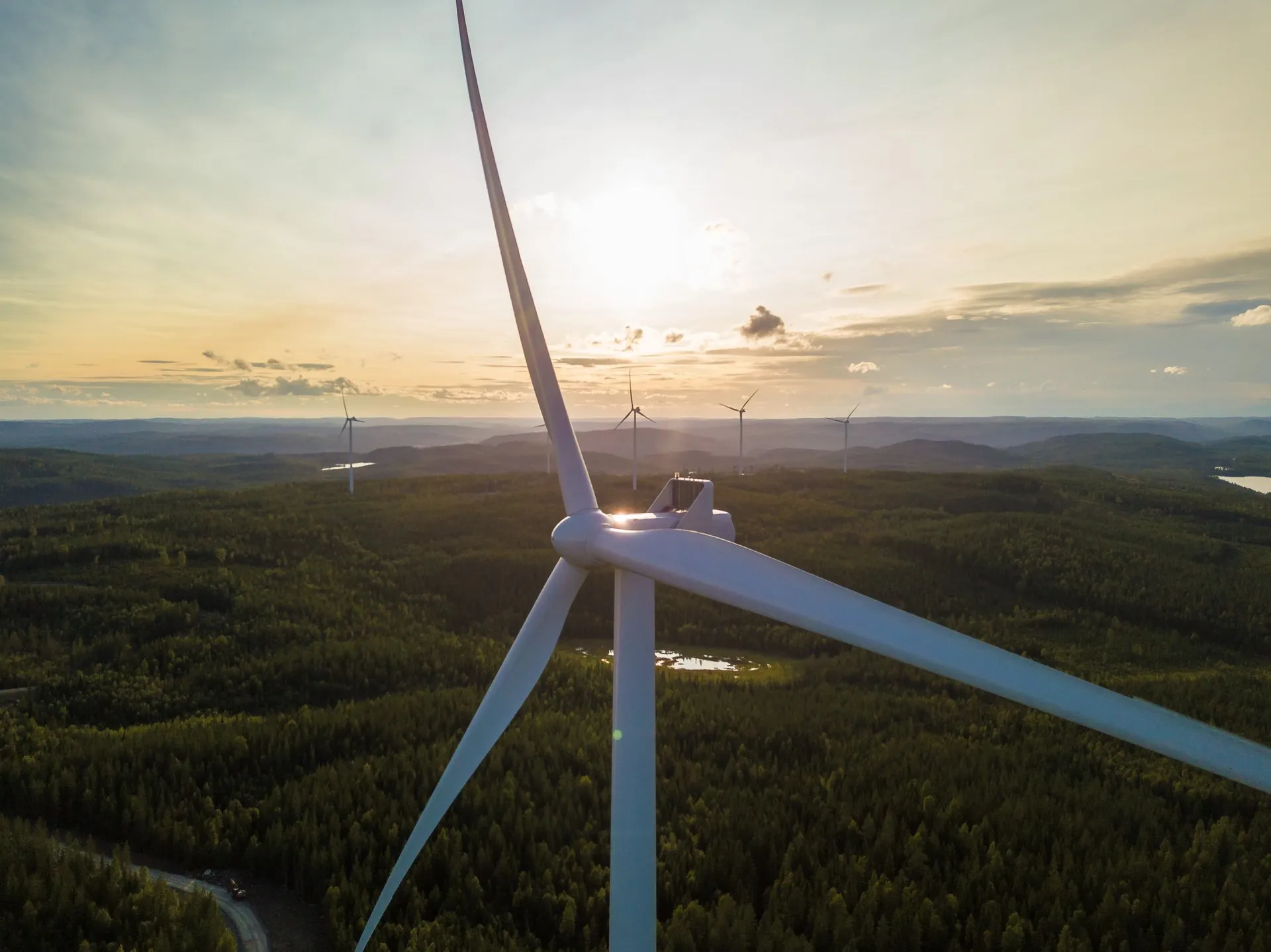 Färdigt vindkraftverk i drift med soluppgång över skogslandskap