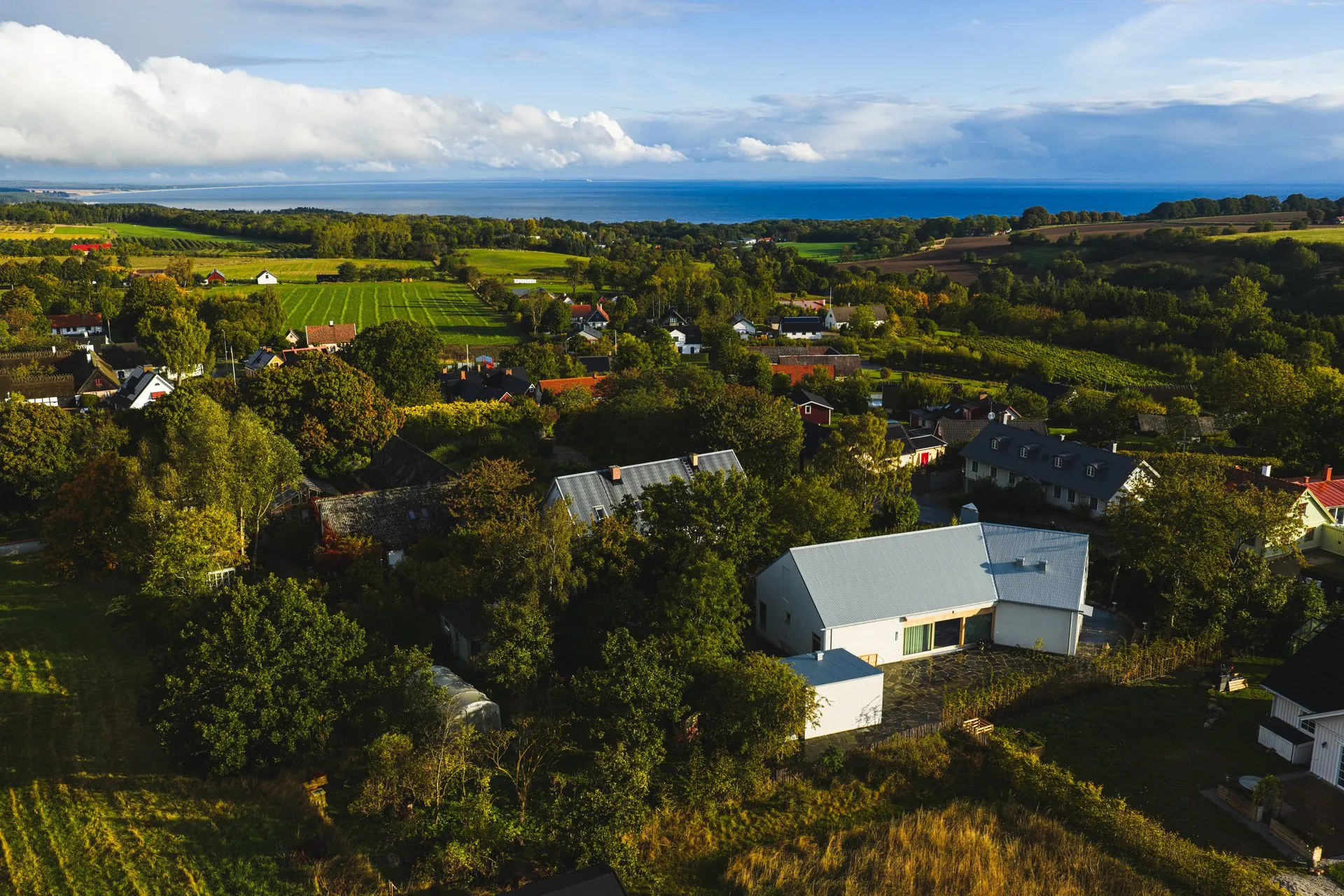 Flygfoto över Mellby på Österlen med nybyggd villa och Östersjön vid horisonten