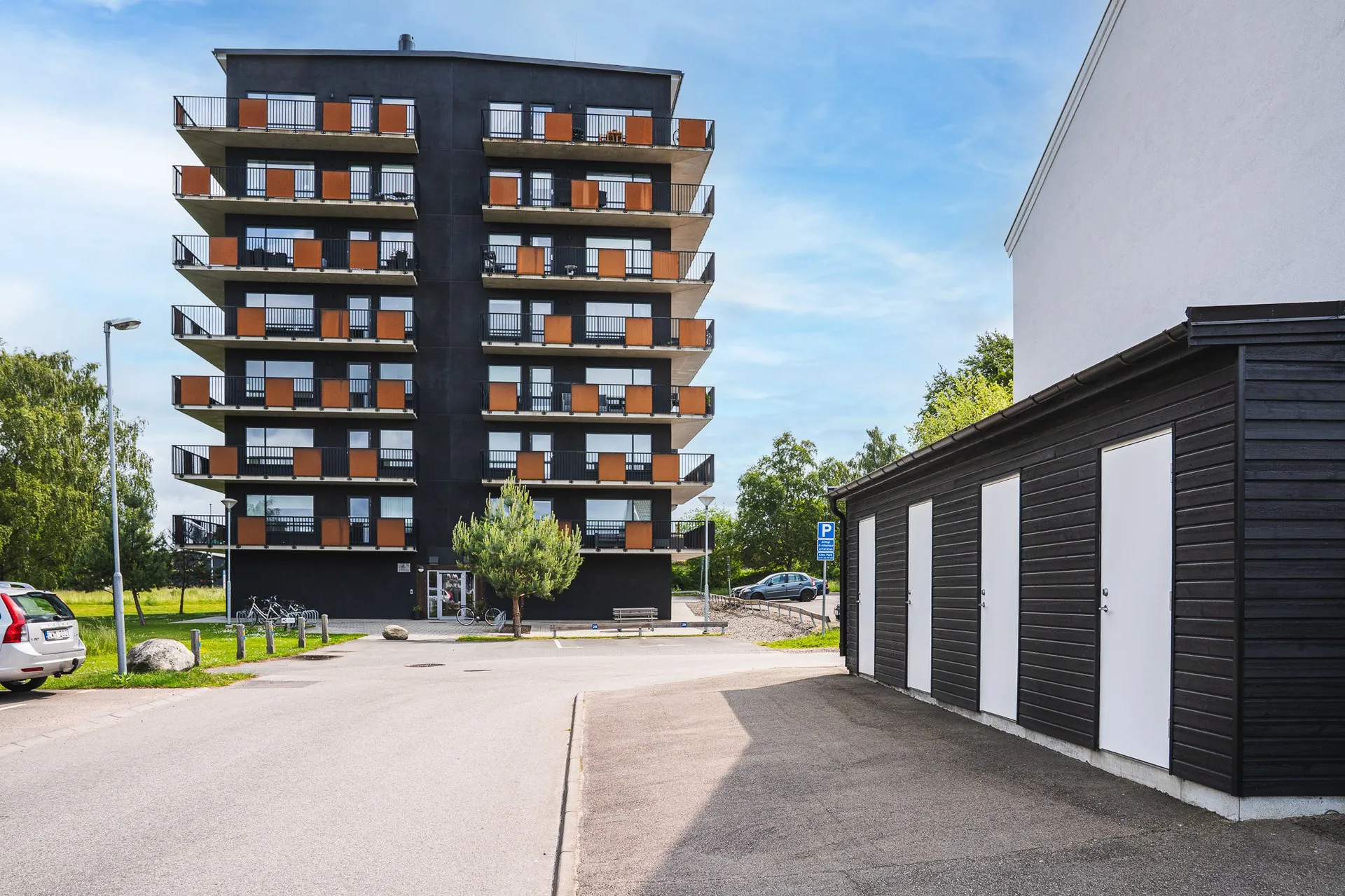 Mörkt punkthus med orange balkongfronter mot blå himmel