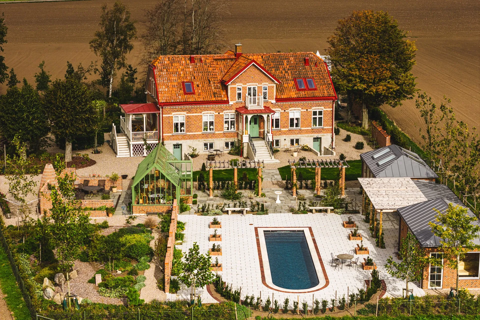 Flygfoto över Hagalind, tegelvilla med trädgård, orangeri och pool