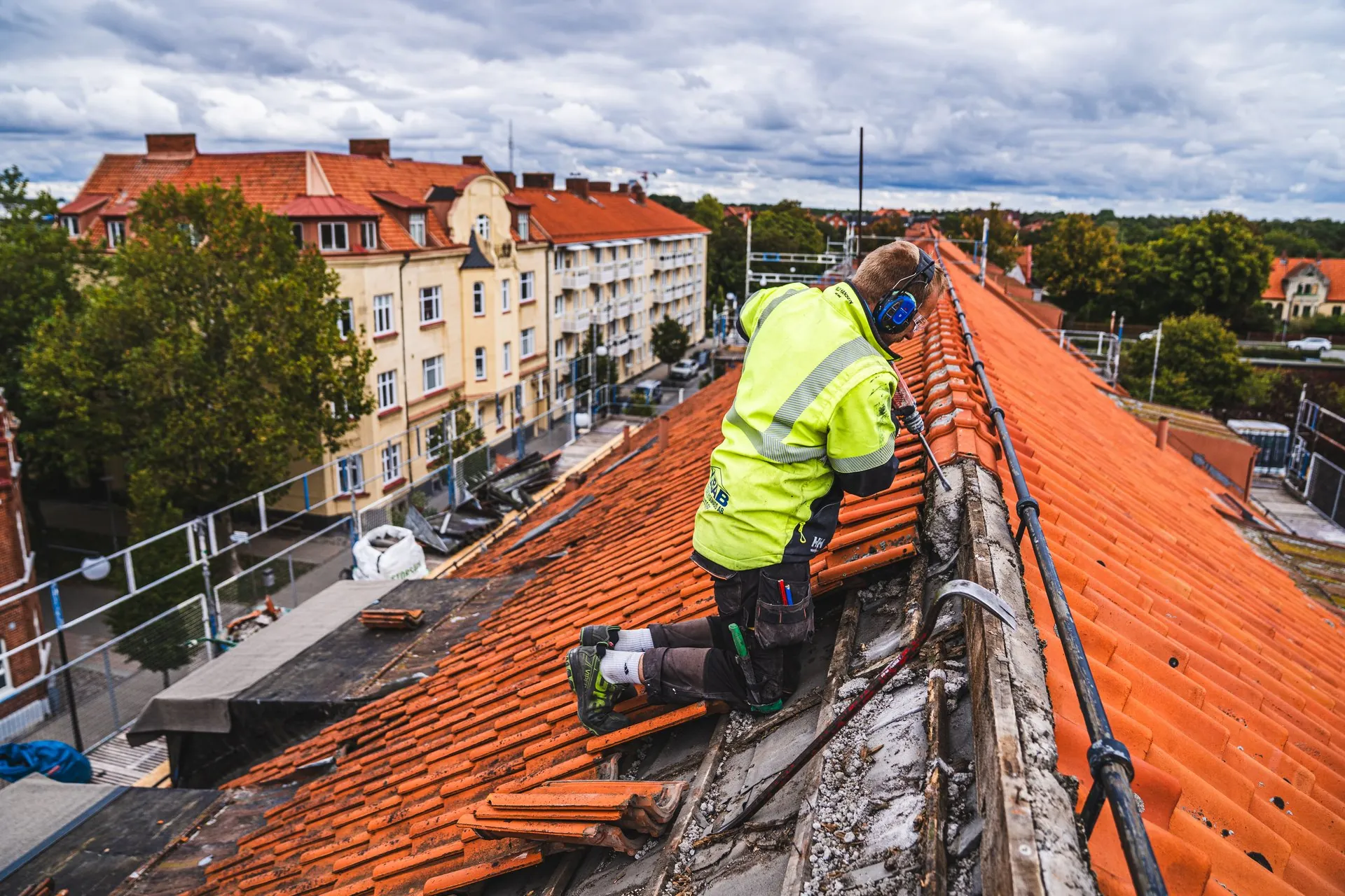 Takläggare i varselkläder lägger tegelpannor högt över hustaken