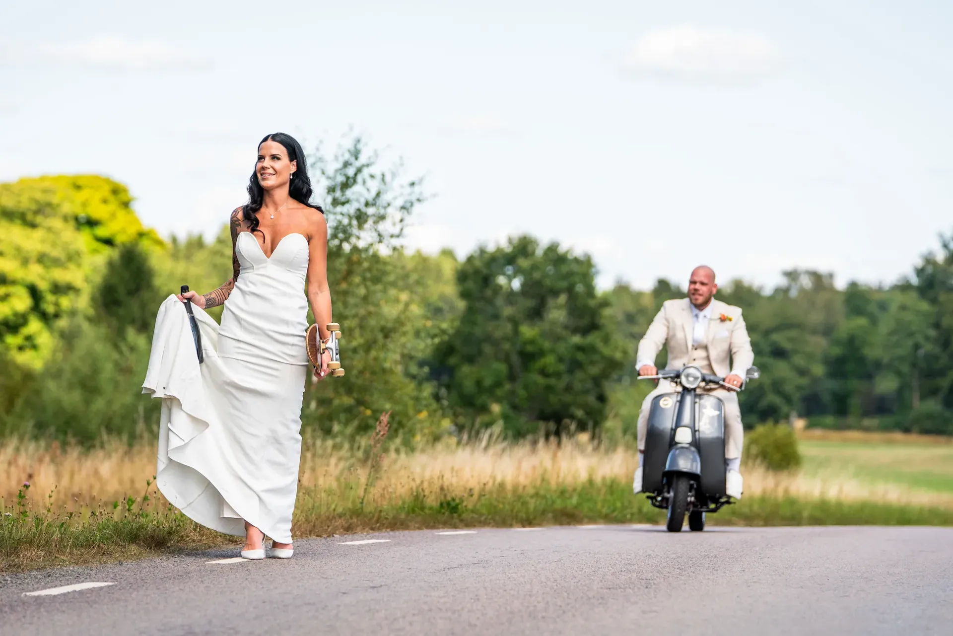 Brud med skateboard på vägen vid Bjära gård i Vinslöv medan brudgummen kör vespa bakom