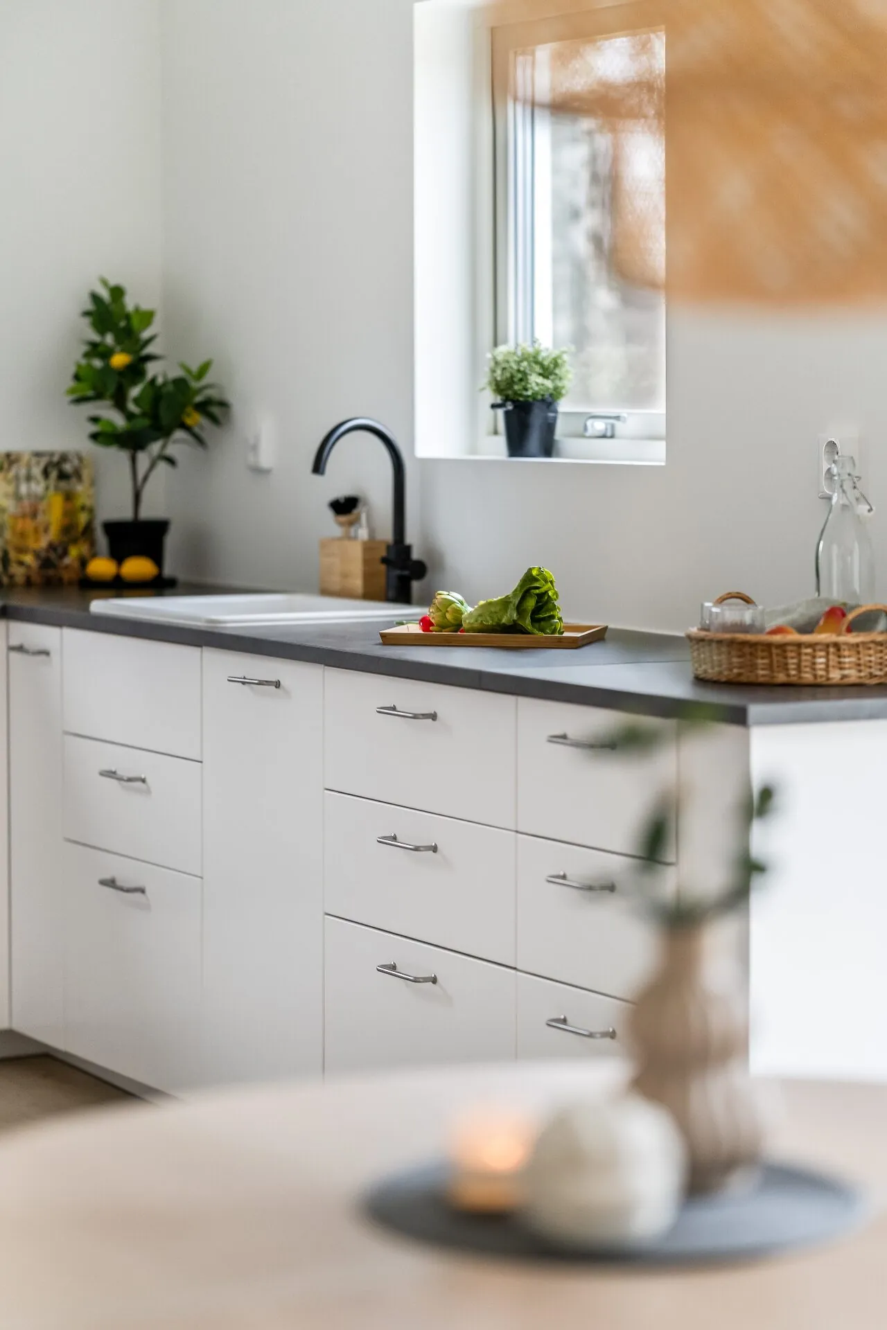 Ljust kök med svart blandare och fönster mot trädgård åt HusmanHagberg
