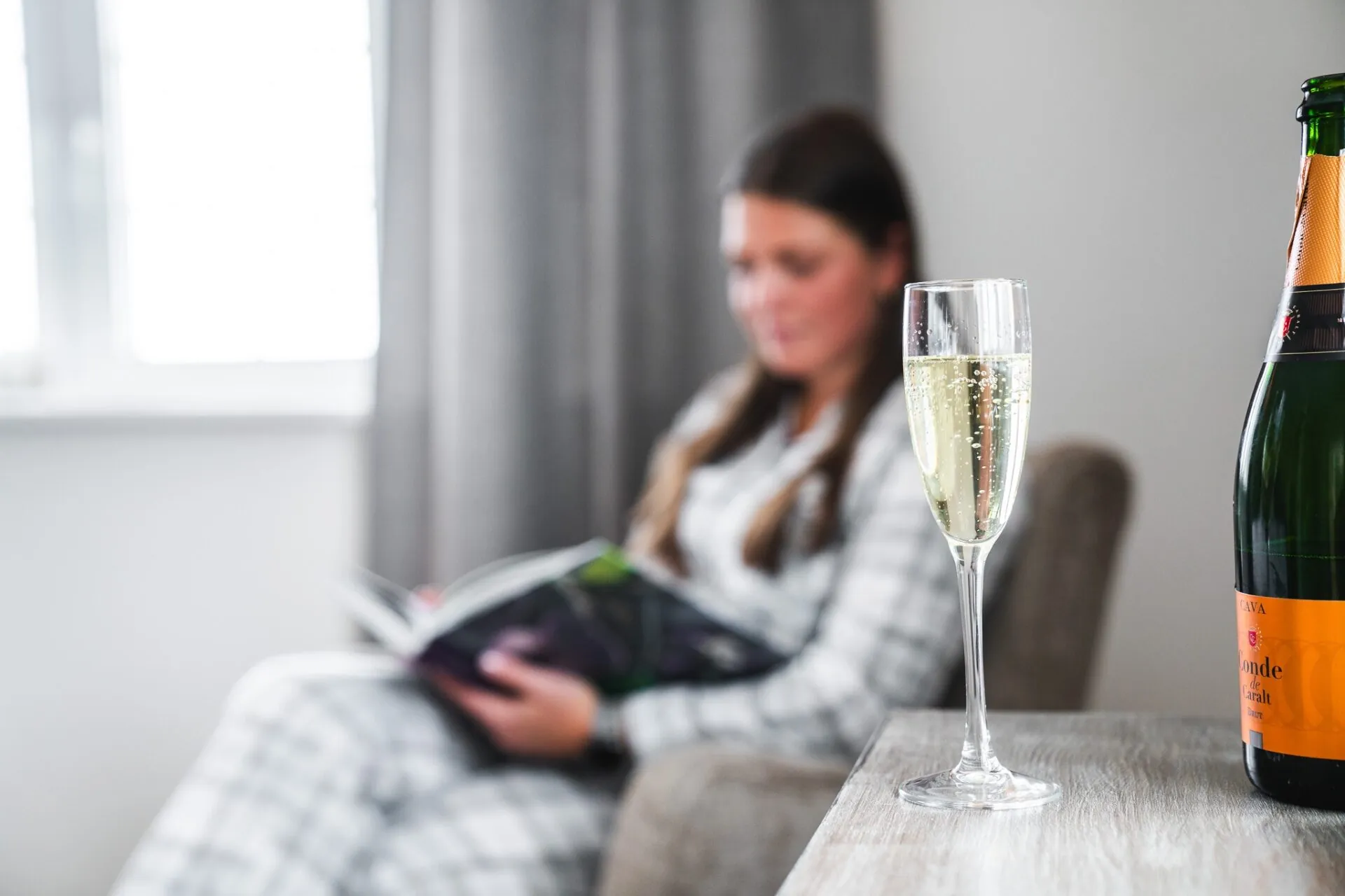 Lifestyle-bild med cavaglas i förgrunden och kvinna som läser i bakgrunden