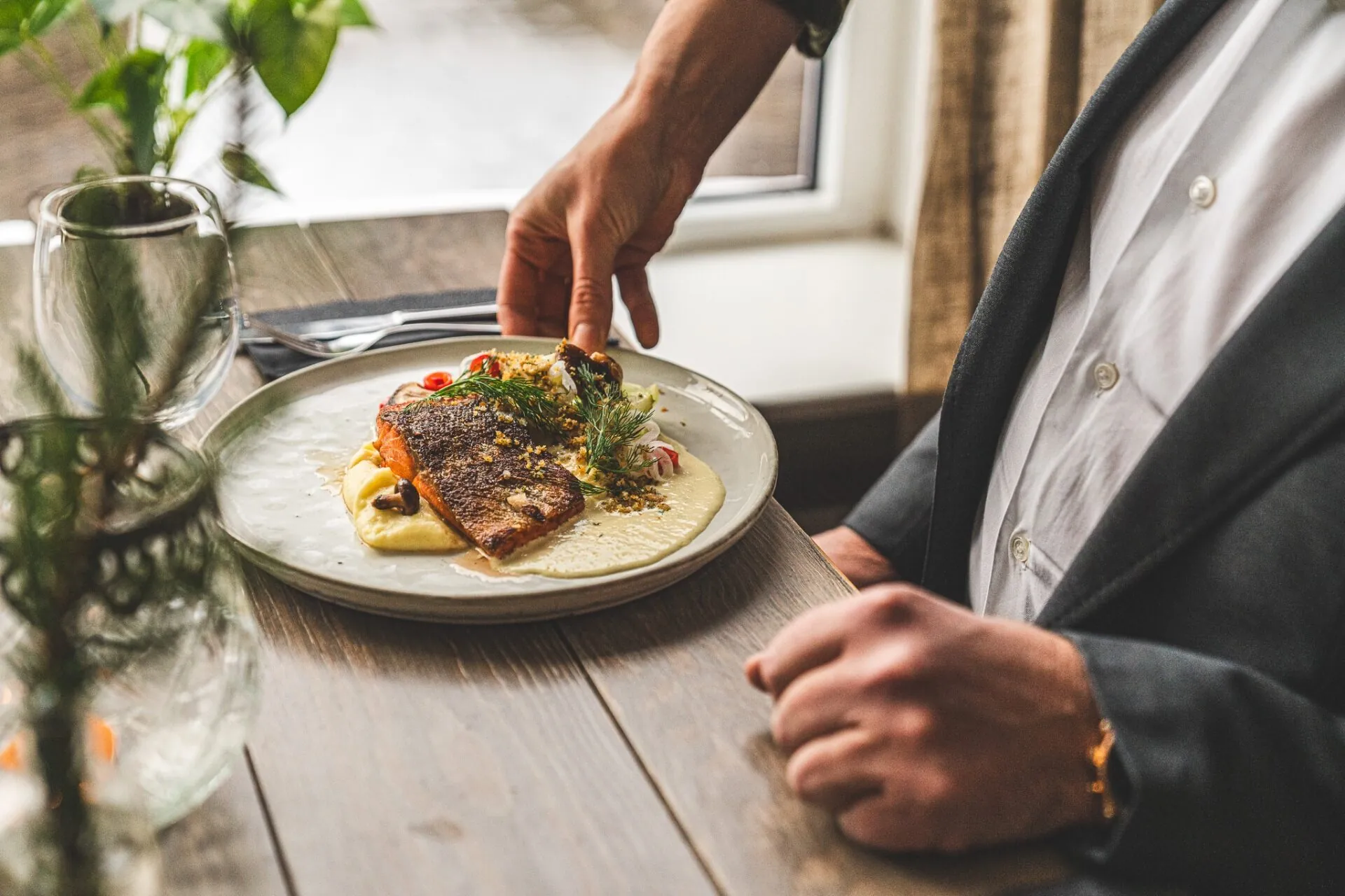 Servering av stekt lax med potatispuré och dill till gäst vid bord