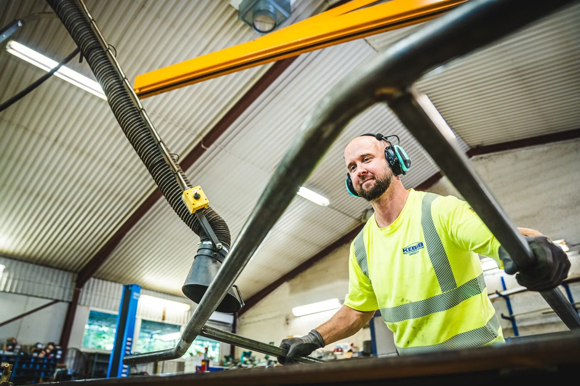 Industriarbetare i varselkläder och hörselskydd vid arbete i verkstad