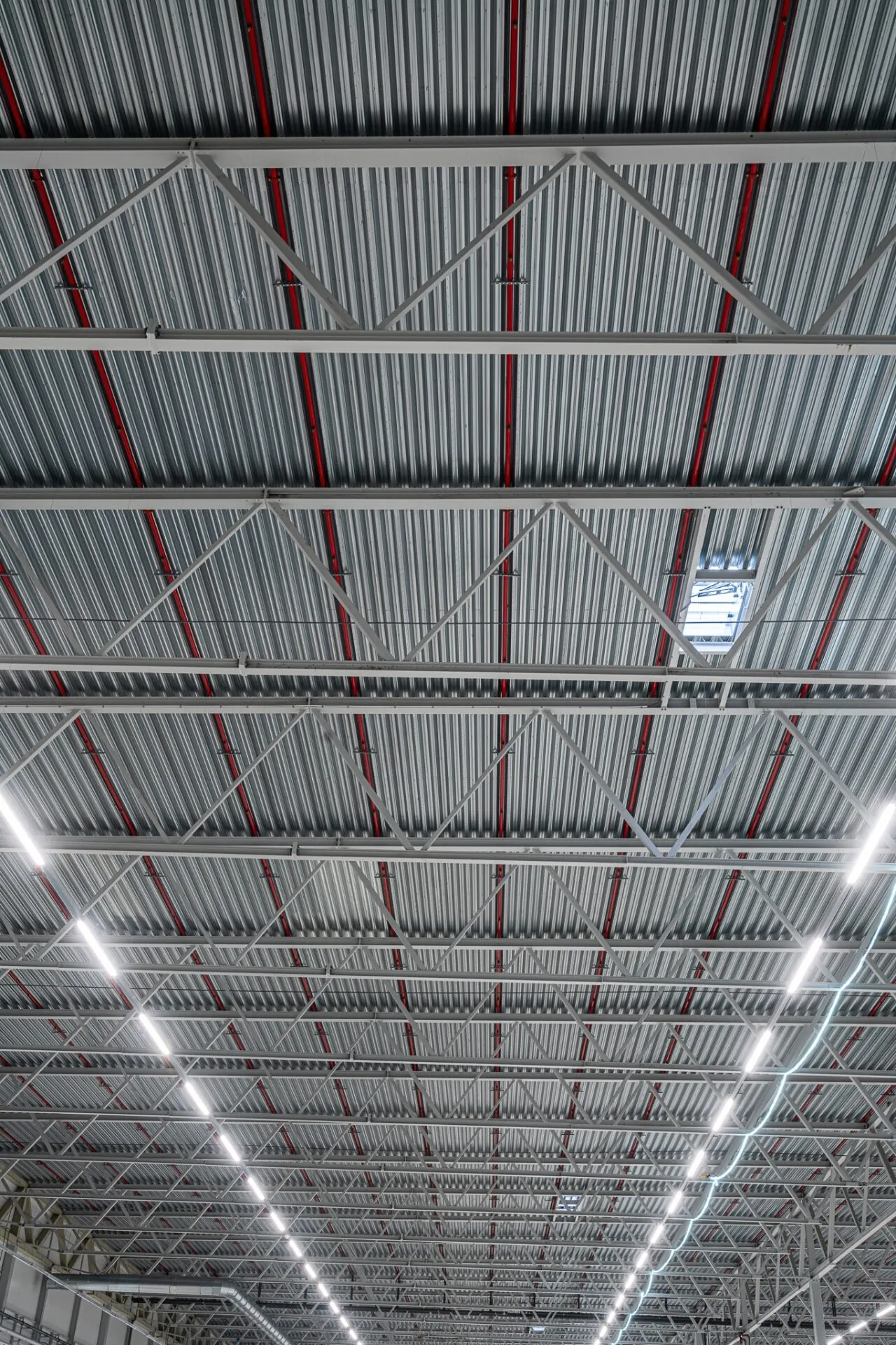 Takkonstruktion i stål med röda detaljer i nybyggd industrihall