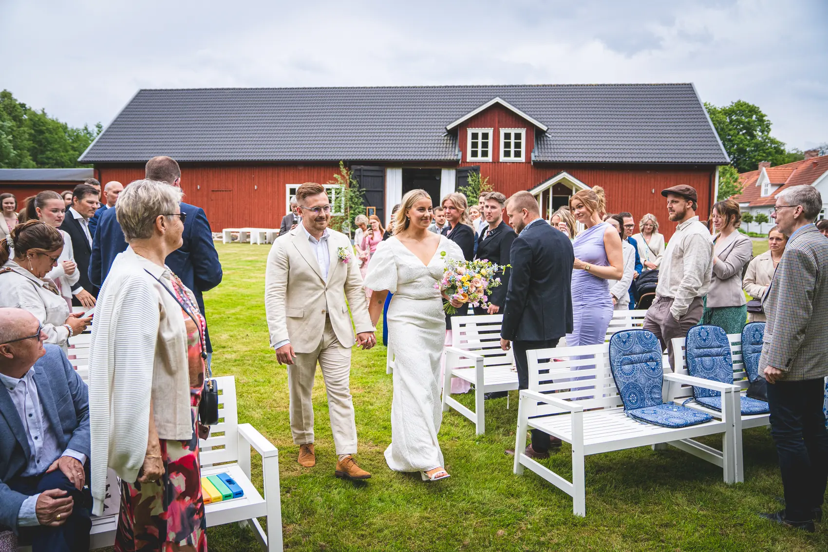 Utomhusvigsel framför den röda ladan på Bjära gård, gäster på vita stolar